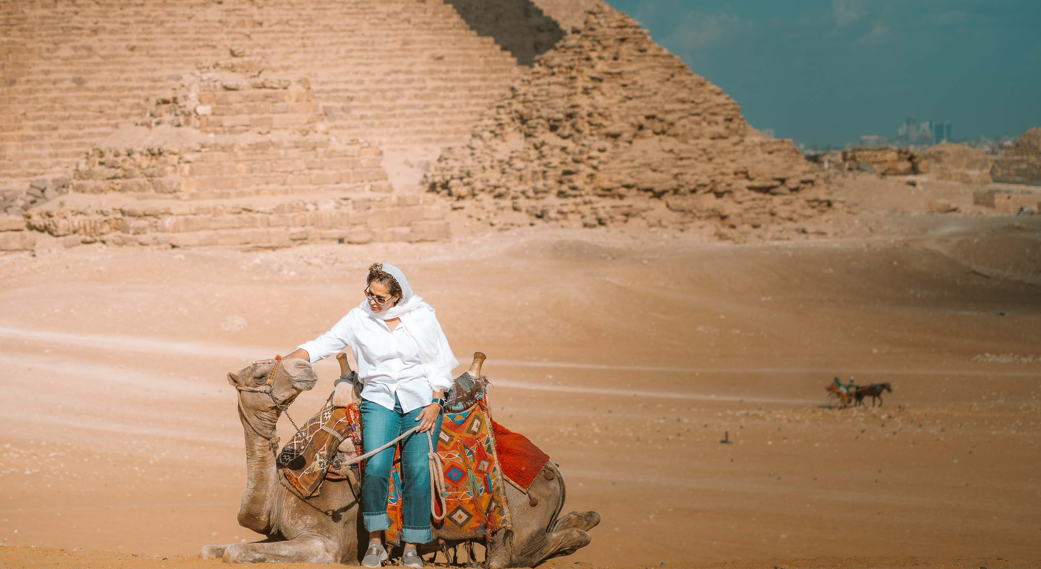 A child riding a camel near a pyramid in Egypt.